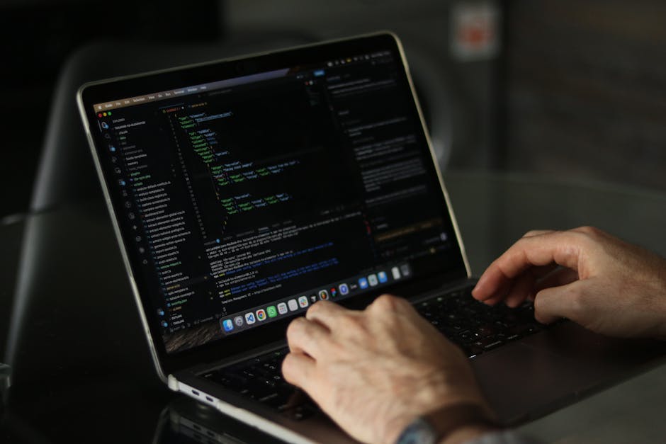 A close-up of a modern laptop computer screen displaying lines of software code within a development environment. The screen shows a code editor with a light theme, with syntax highlighting in various